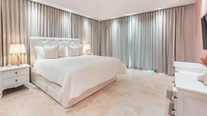 Une chambre à coucher moderne avec un grand lit, une table de chevet avec une lampe et une commode.