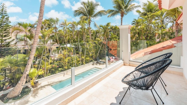 Un balcon avec une piscine, entouré de palmiers et surplombant un ciel dégagé.