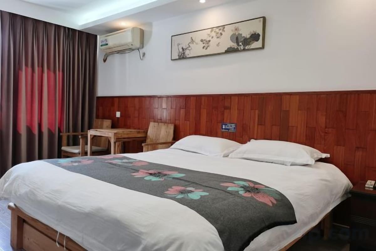 Une chambre d’hôtel équipée d’un lit, d’un bureau, d’une chaise, d’une table de chevet et d’un climatiseur fixé au mur.