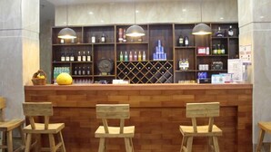 Una zona de bar con sillas de madera, estantes llenos de botellas y un frutero.