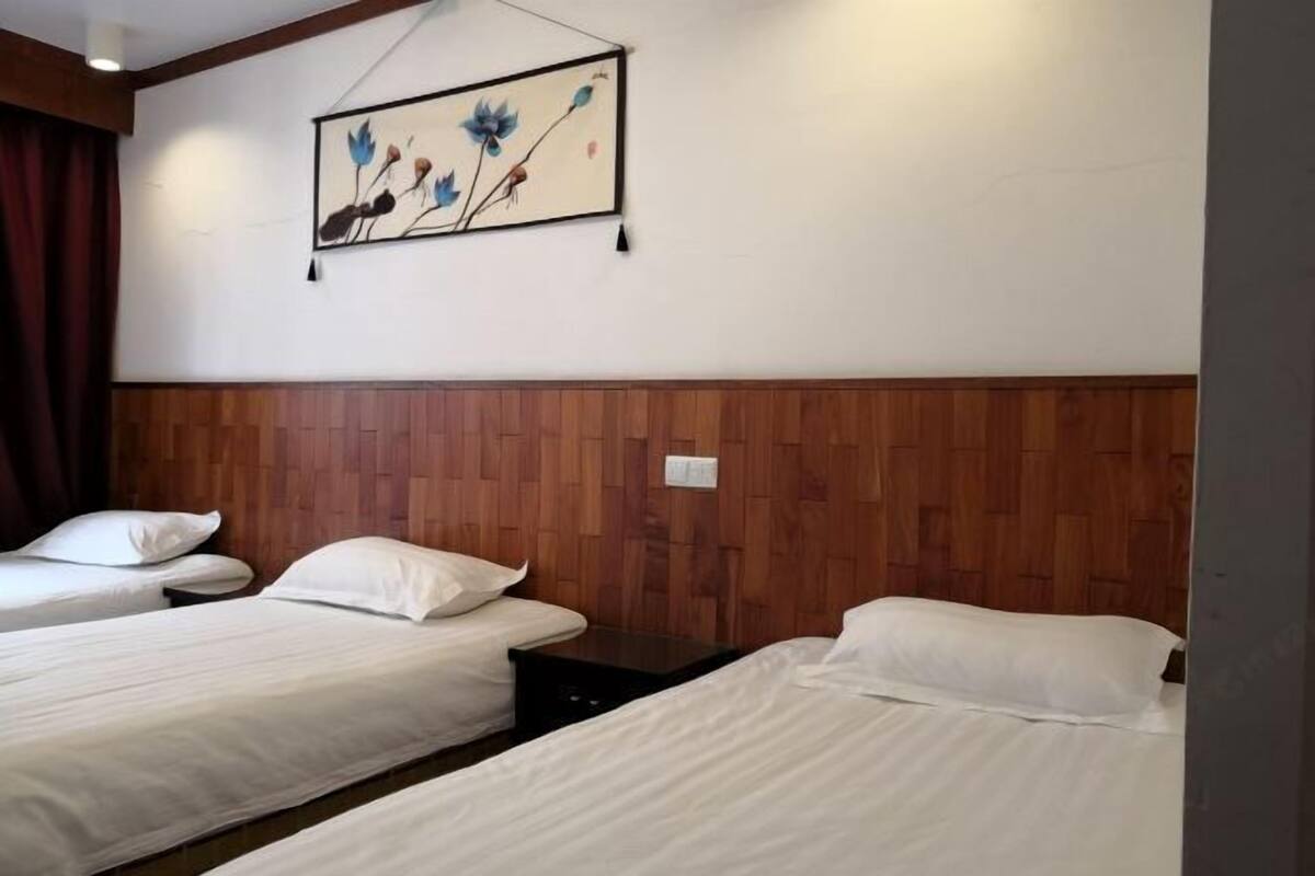 Habitación de hotel con dos camas, paneles de madera en las paredes, un cuadro sobre las camas y una mesita de noche.