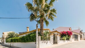 Un edificio residencial con fachada blanca, techo rojo y una palmera en primer plano.