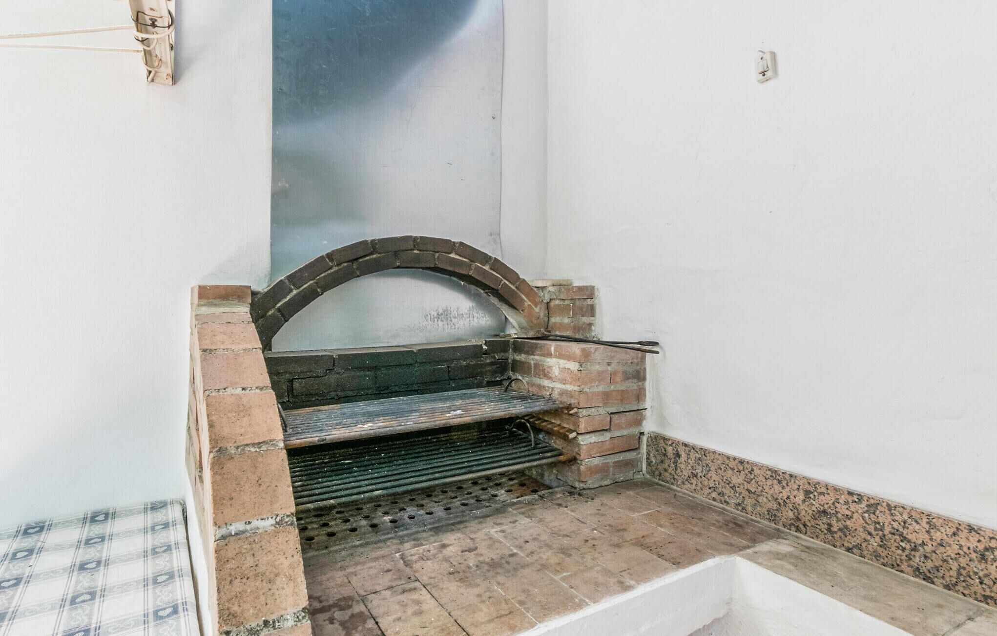 A small, enclosed space with a brick oven, a metal grate, and a tiled floor.