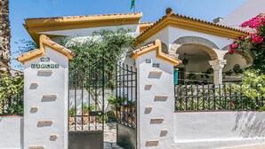 A white building with a gate, labeled "De Carlos," and a number "35" on the wall.