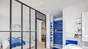 Um banheiro moderno com pia branca, espelho e box do chuveiro azul.