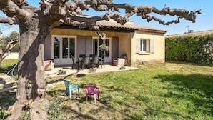 Una casa con un patio, muebles de exterior y un árbol.
