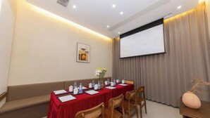 Una sala de conferencias con una mesa larga, sillas, una pantalla de proyector y un atril.
