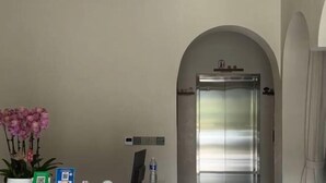 Un área de recepción con una orquídea en maceta, una botella de agua y un código QR en la pared.