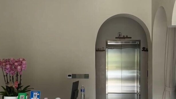A reception area with a potted orchid, a water bottle, and a QR code on the wall. - Huangjia Inn (Wuyuan)