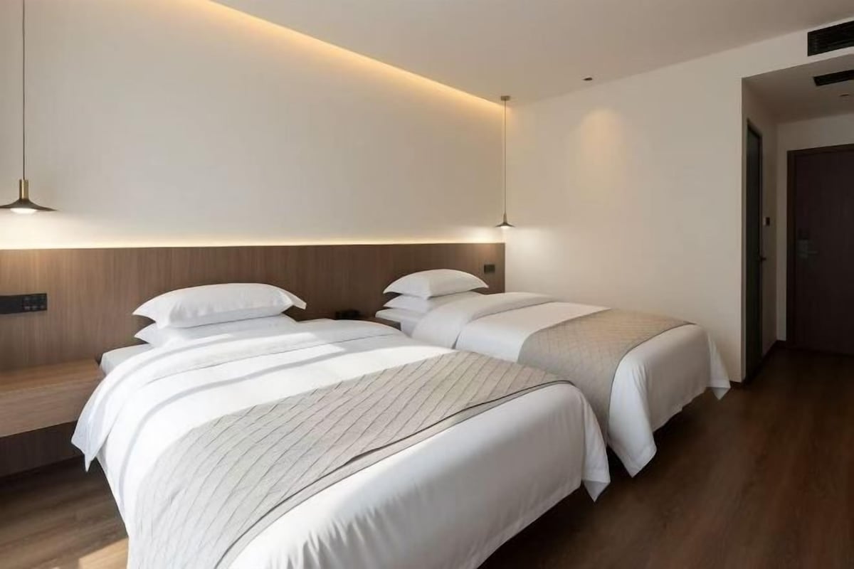 A hotel room with two beds, a wooden headboard, and a bedside table.