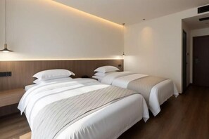 A hotel room with two beds, a wooden headboard, and a bedside table.