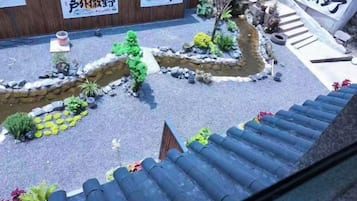 A courtyard with a small stream, potted plants, and a traditional tiled roof.
