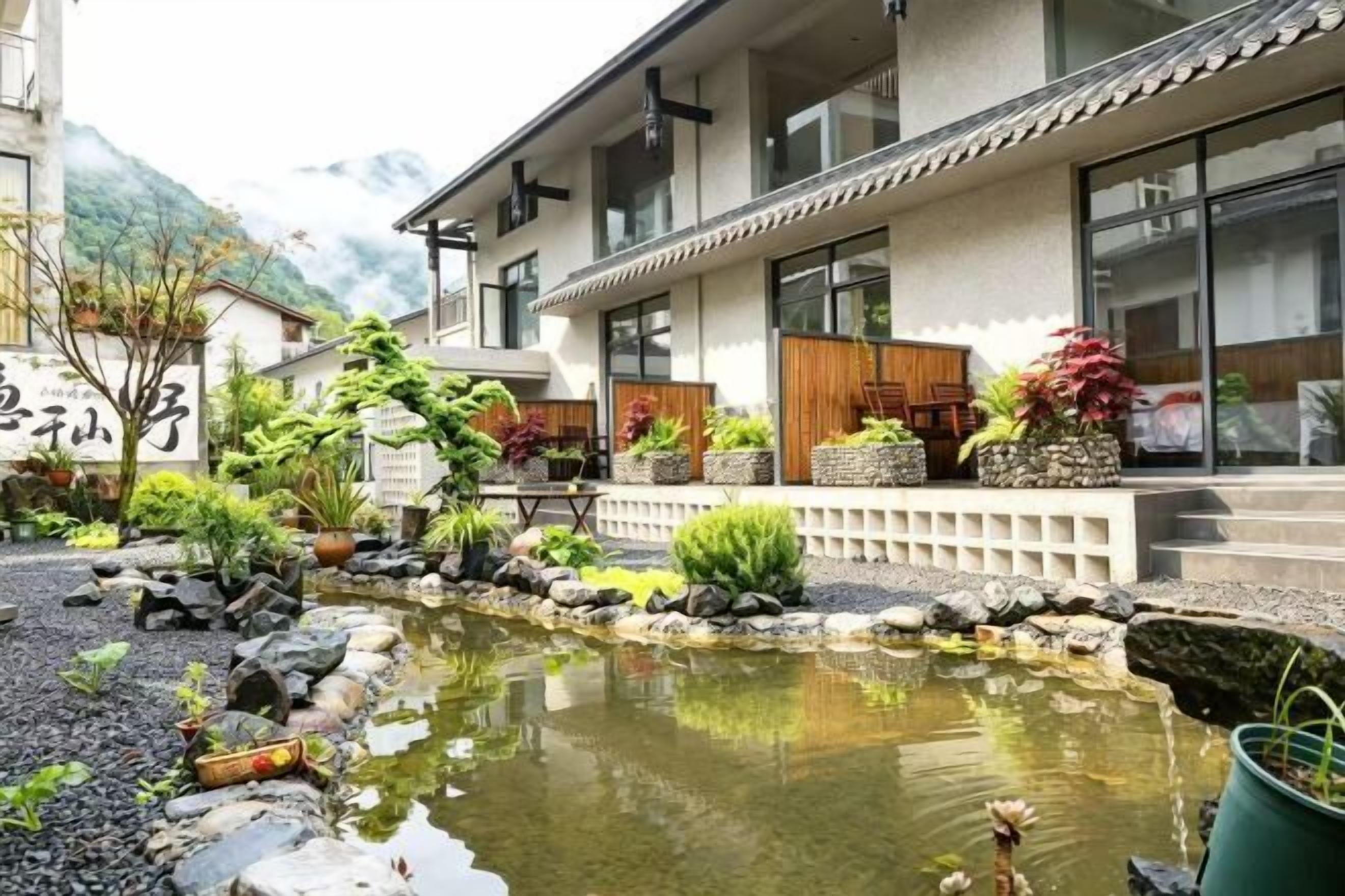 A traditional Japanese building with a koi pond and potted plants.