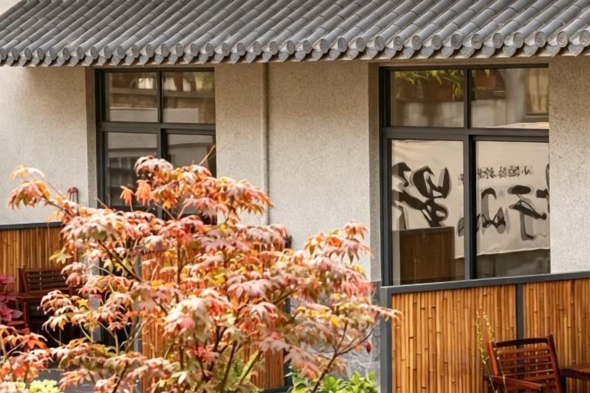 A traditional building with a tiled roof, large windows, and a wooden fence.