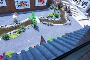 A traditional Japanese garden with a stone pathway, small water features, and various plants.