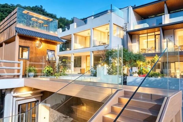 A modern multi-story building with a glass facade, outdoor seating area, and a staircase leading to an upper level.