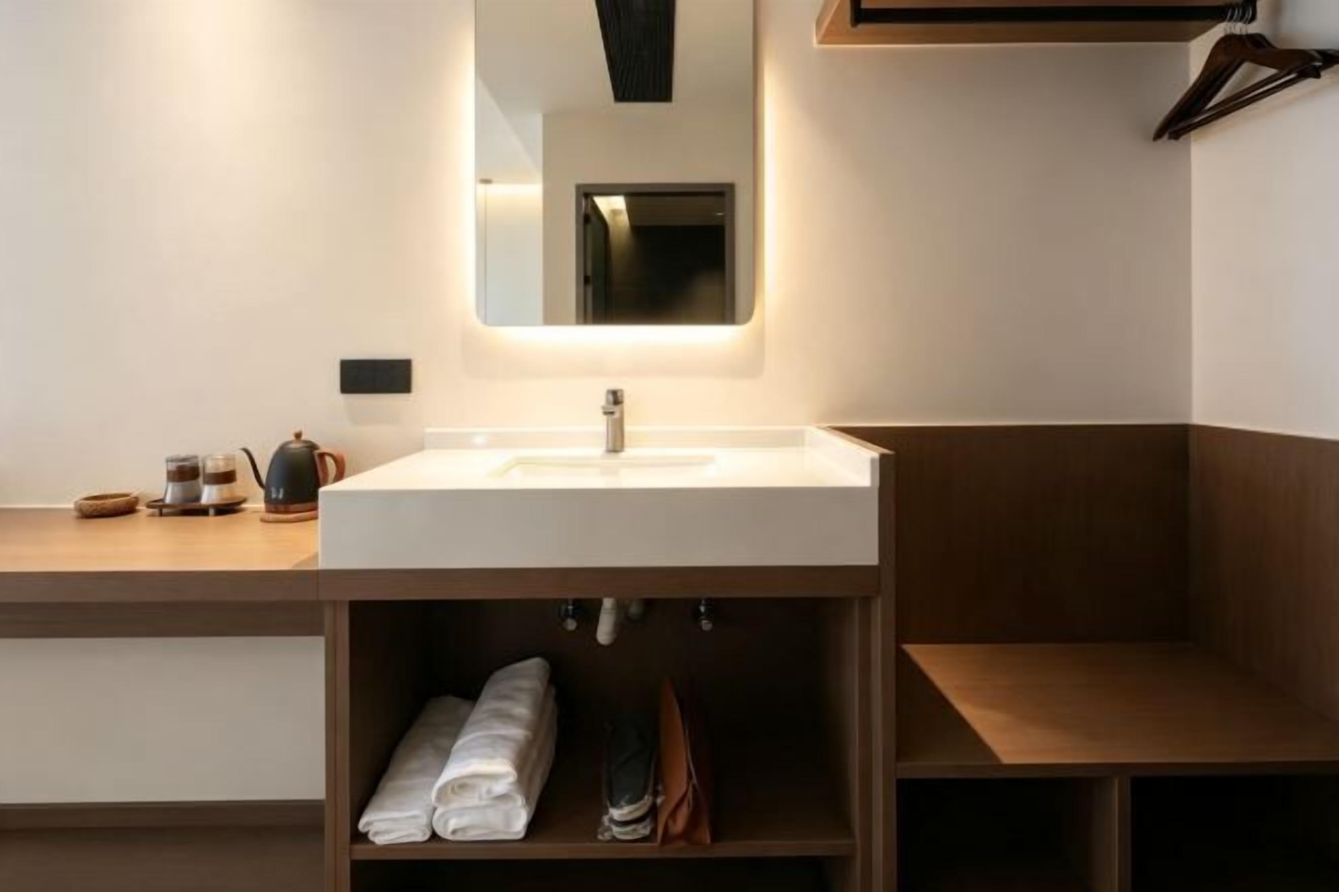 A modern bathroom with a white sink, a mirror, and a towel rack.