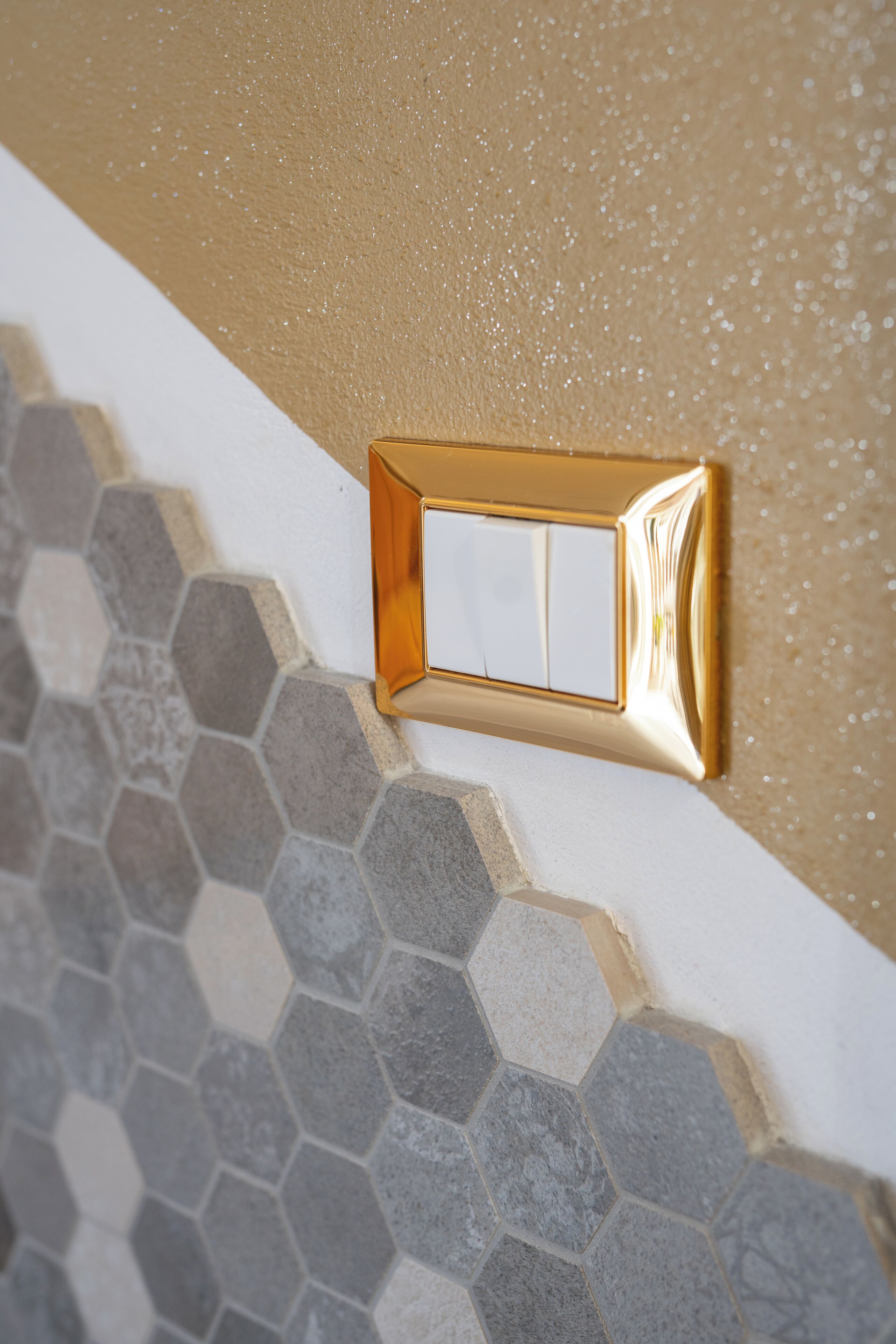 A wall switch on a textured surface with hexagonal tiles.