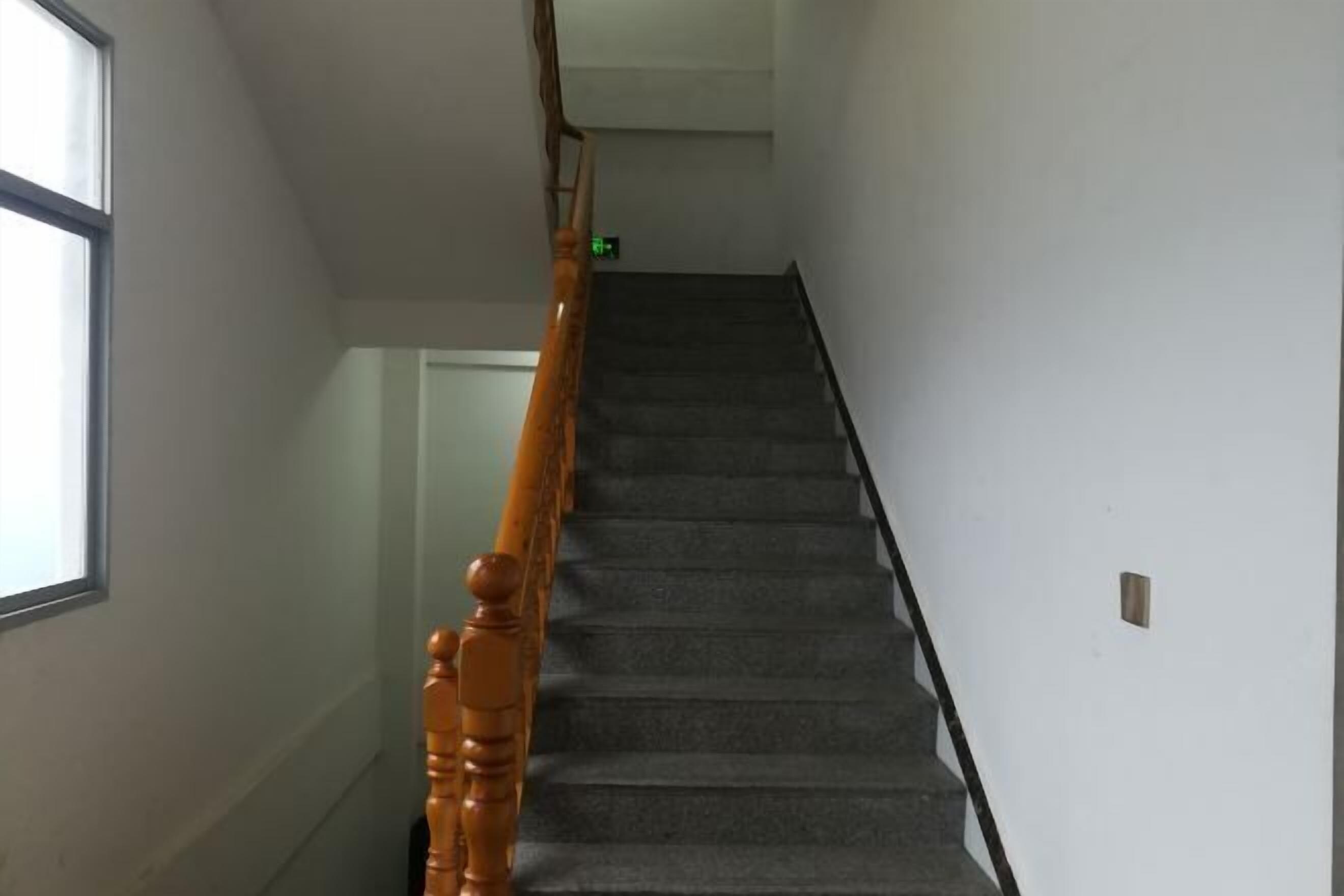 A staircase with a wooden handrail and carpeted steps leading to an upper floor.