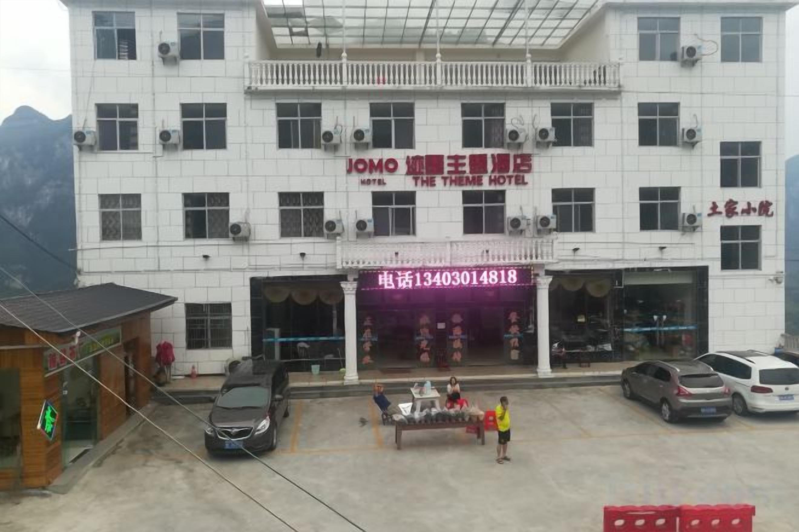 A hotel with a two-story structure, a balcony on the upper floor, and a ground-level entrance with a reception desk.