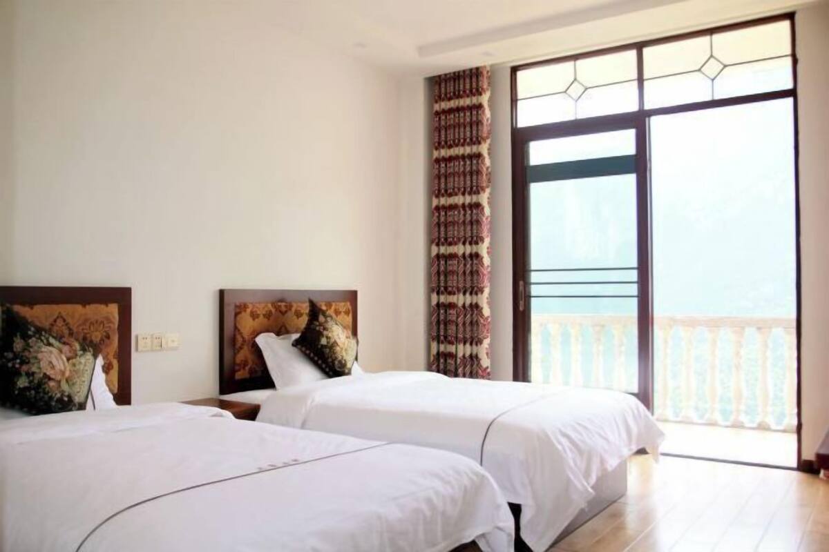 Una habitación de hotel con dos camas, un ventanal grande y un balcón.