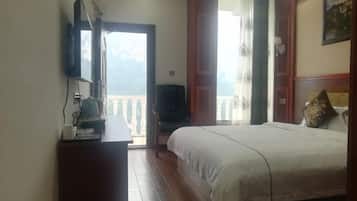 A bedroom with a bed, a TV on a stand, a wooden dresser, and a balcony with a view.