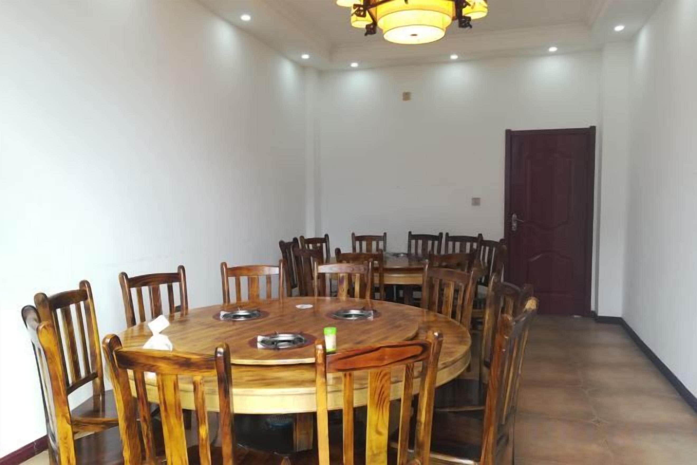 Una sala de conferències amb una taula rodona gran, voltada per cadires, una làmpada penjant i una porta al fons.