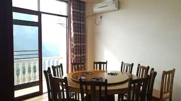 A dining area with a round table and chairs, a window with a view, and an air conditioning unit on the wall.