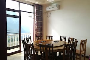 Un comedor con una mesa redonda y sillas, una ventana con vistas, y un equipo de aire acondicionado en la pared.