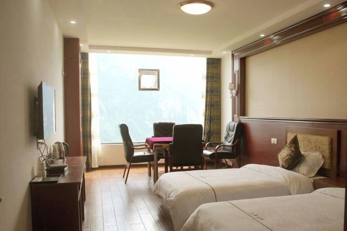 Una habitación de hotel con dos camas, un escritorio con silla, televisión y ventana con vistas.