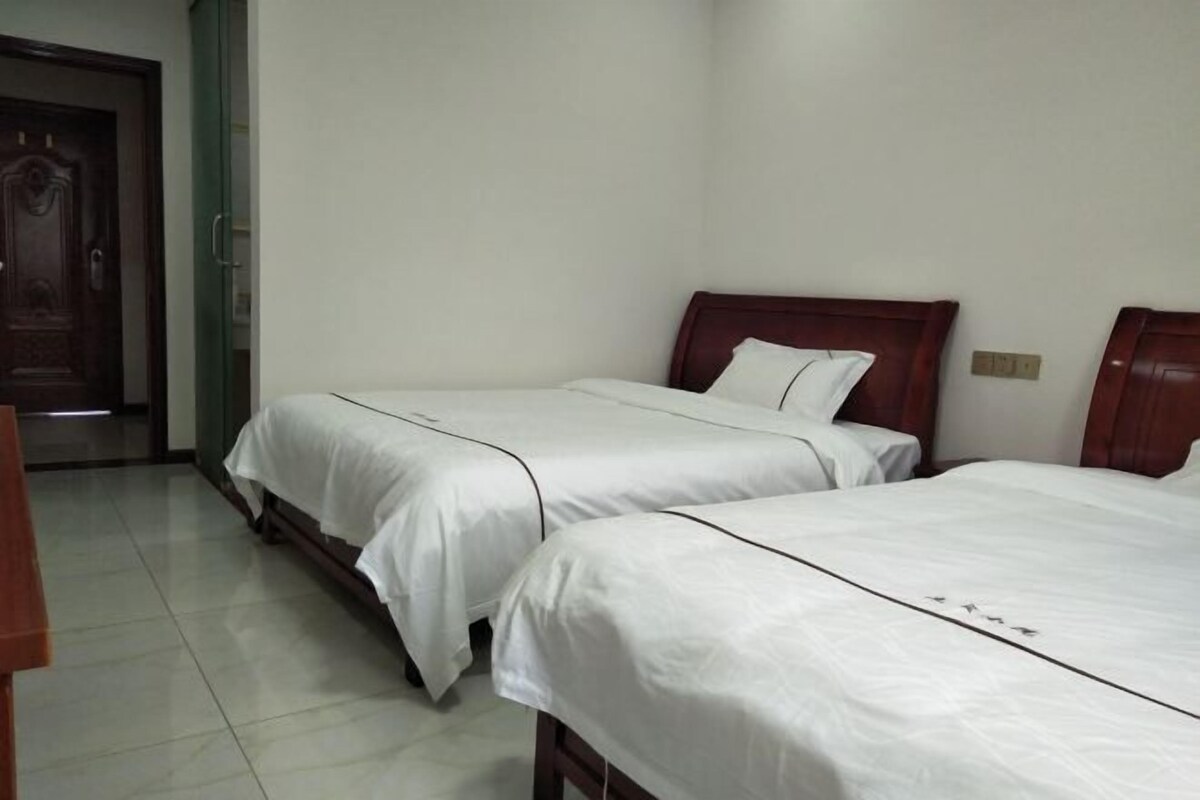 Ein Hotelzimmer mit zwei Einzelbetten, einer Holztür und einem gefliesten Boden.