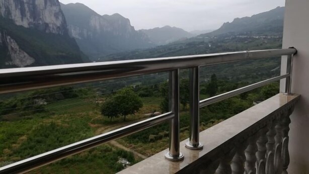 A balcony with a metal railing overlooking a mountainous landscape.
