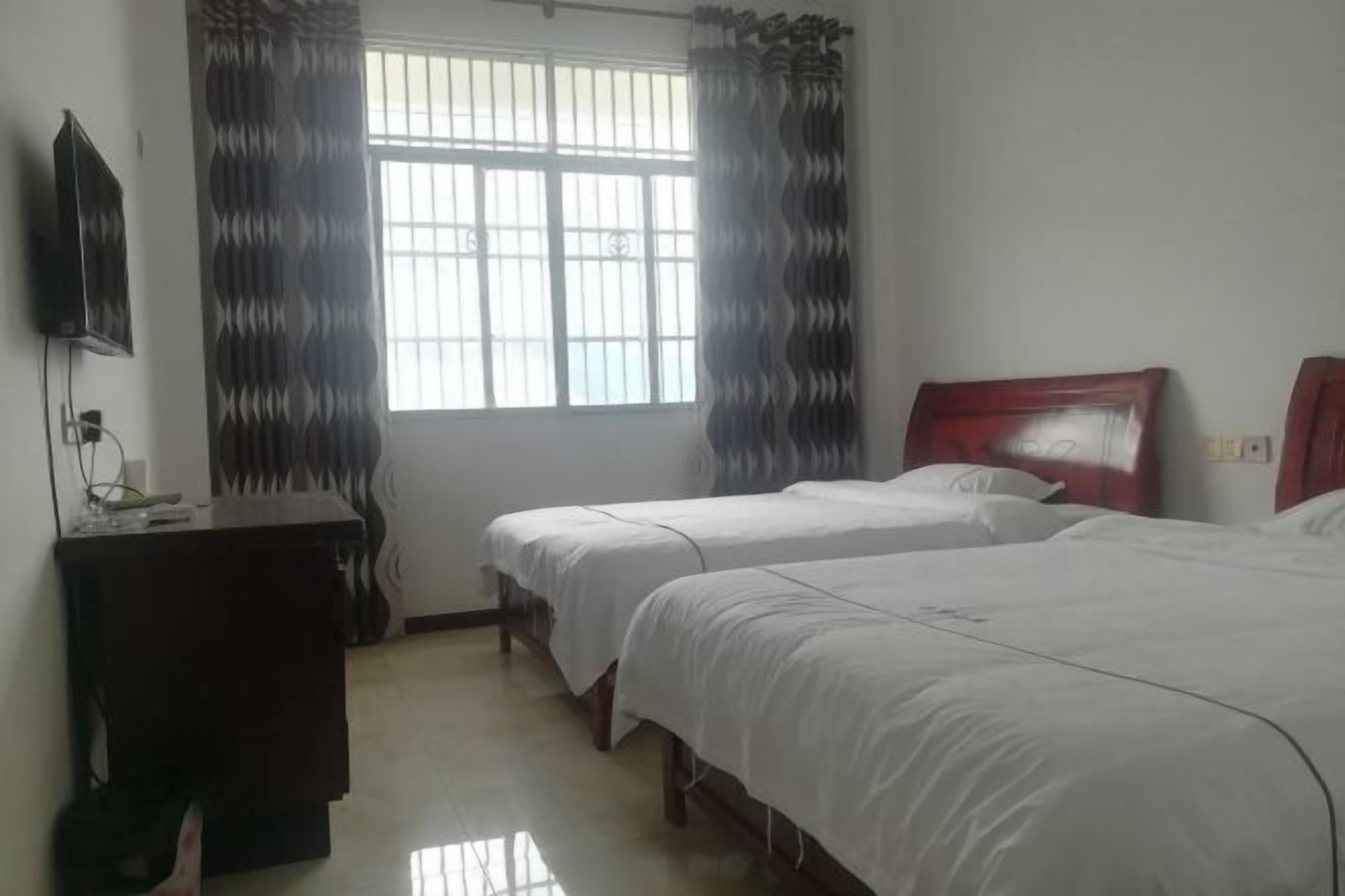 Una habitación de hotel con dos camas, cabecero de madera, una mesita de noche y un televisor montado en la pared.