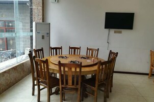 Un salón de conferencias con una mesa redonda de madera y sillas, un televisor de pantalla plana montado en la pared y un ventanal con vistas al exterior.