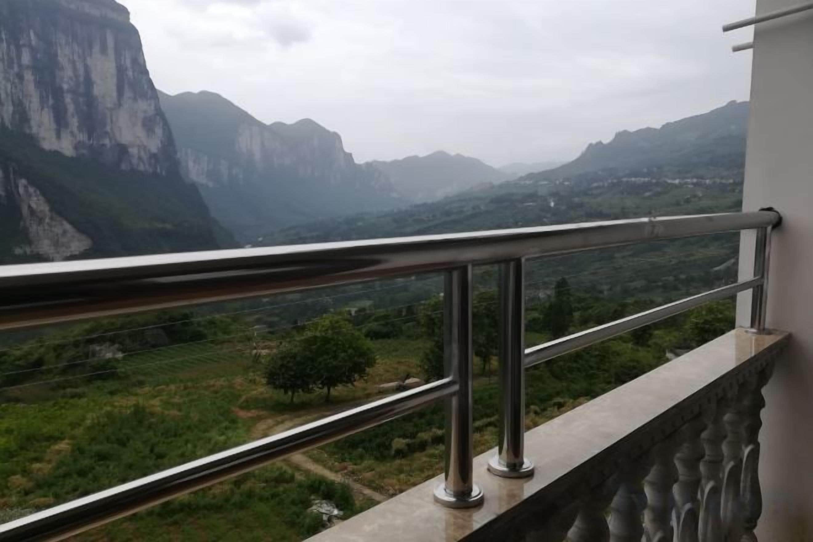 A balcony with a metal railing overlooking a mountainous landscape.