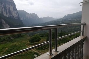 Un balcón con barandilla de metal que da a un paisaje montañoso.