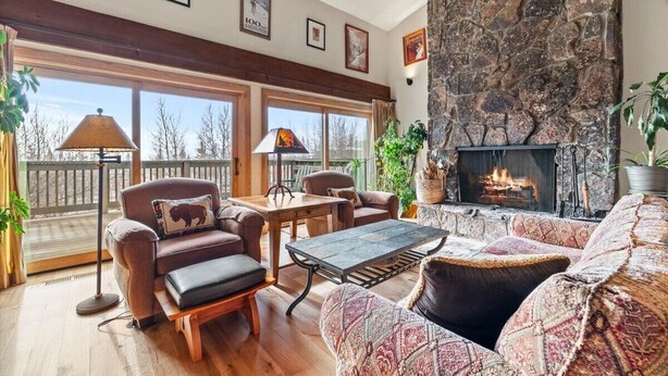 Una sala de estar acogedora con chimenea de piedra, ventanas amplias y un mobiliario cómodo.