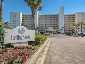 Entrada de hotel con un cartel que dice "Sterling Sands" y un estacionamiento al frente.