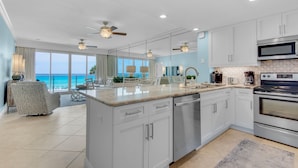 A modern kitchen with white cabinets, stainless steel appliances, and a large island.