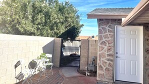 A patio area with a table and chairs, a stone wall, and a door.
