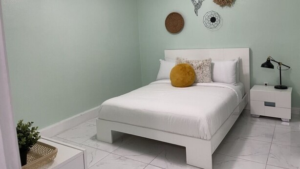 A bedroom with a bed, a nightstand, a wall-mounted air conditioner, and decorative wall art.