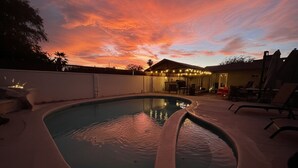 A swimming pool with a curved edge, surrounded by a patio area with outdoor furniture and string lights. - 4BR, 2-house compound close to UA, Downtown Tucson (Tucson)