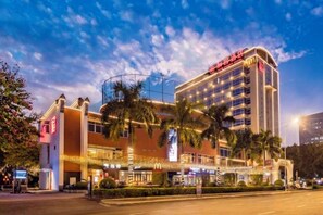 A multi-story hotel with a prominent McDonald's logo, a curved corner design, and a well-lit entrance area. - Yishan Meiyuan Hotel (Fuzhou)