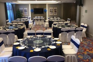 A conference room with round tables, white chairs, and a carpeted floor. - Yishan Meiyuan Hotel (Fuzhou)