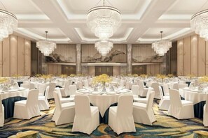 A banquet hall with round tables, white chairs, chandeliers, and floral centerpieces. - Yishan Meiyuan Hotel (Fuzhou)