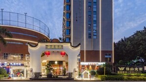 L’entrée d’un hôtel au design moderne, caractérisée par une façade incurvée et une entrée imposante agrémentée d’une décoration de Noël.