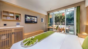 Une chambre d’hôtel équipée d’un lit, d’une télévision, d’un bureau et offrant une vue sur un balcon avec des sièges d’extérieur.