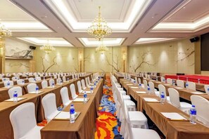 Uma sala de conferências com mesas, cadeiras e garrafas de água dispostas em fileiras.