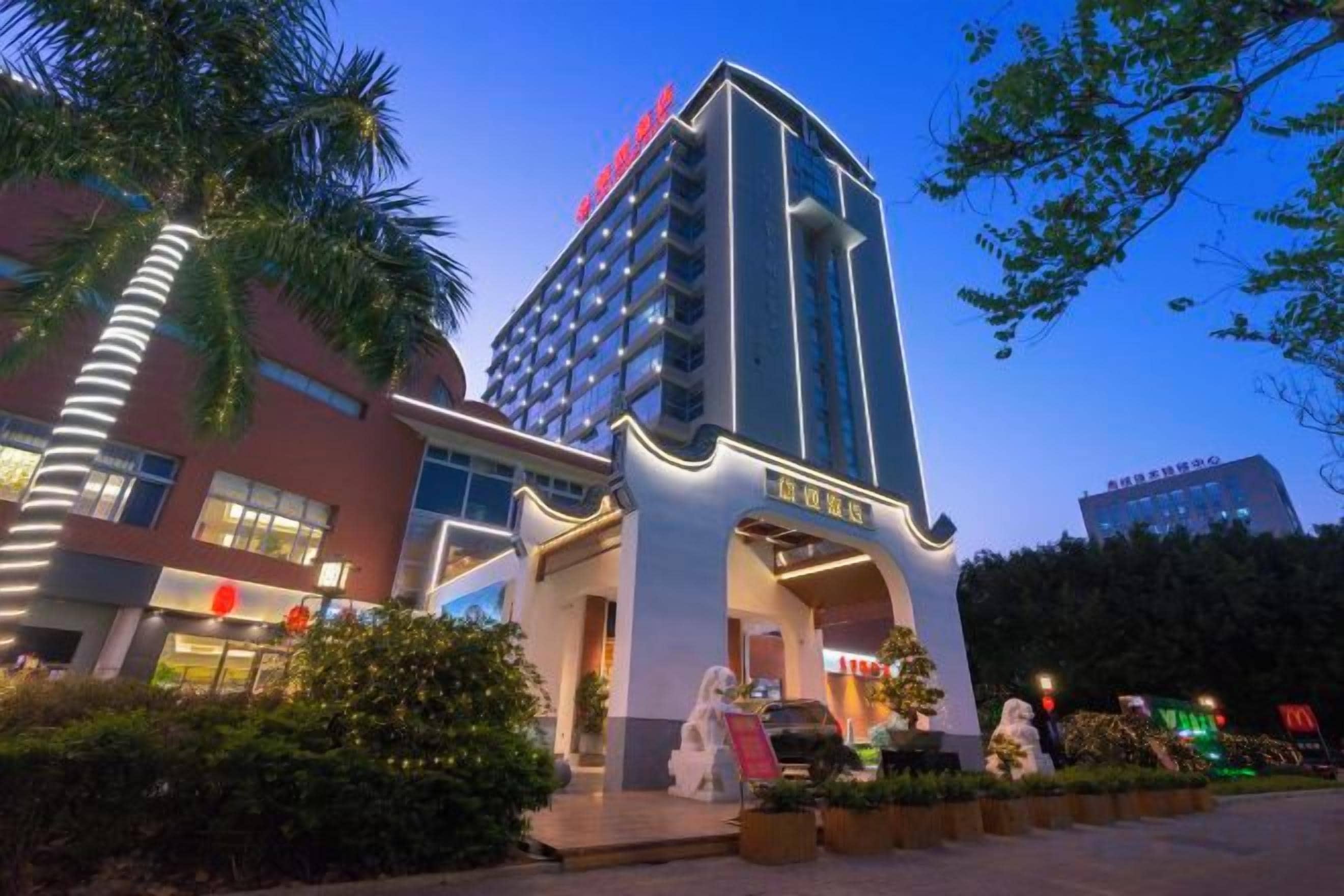 Un hotel de varios pisos con una entrada destacada, un letrero grande y una fachada bien iluminada.