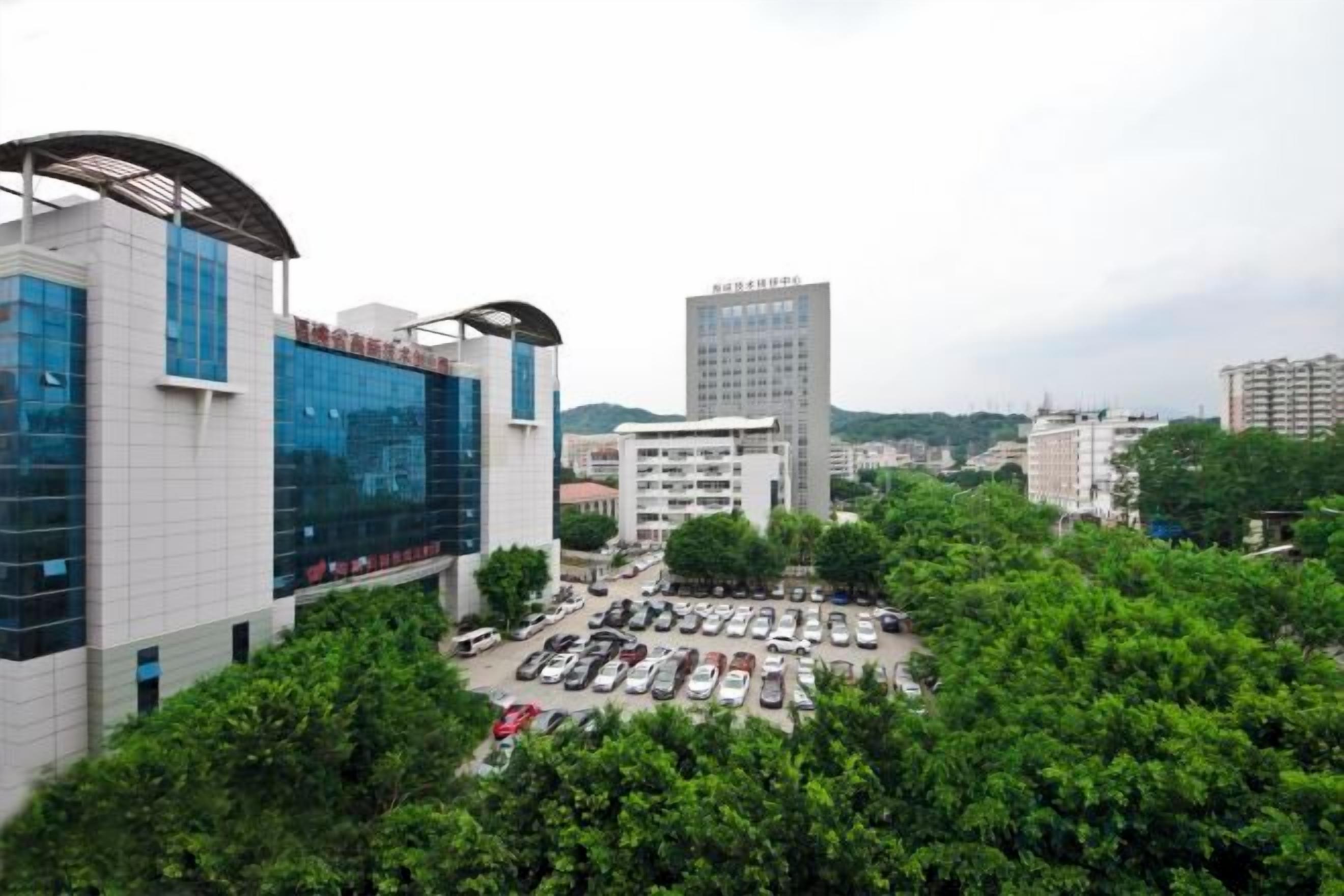 A parking lot with several cars, surrounded by trees and buildings.
